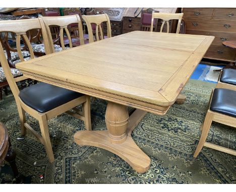 A contemporary light Oak pull-out extending Dining Table, standing on heavy turned legs united by a central stretcher, 39 3/8
