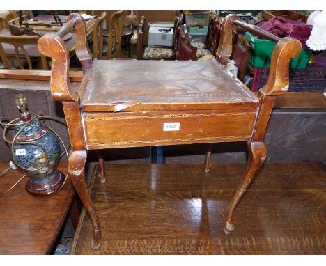 A Satinwood Piano Stool with light and darkwood stringing and standing on cabriole legs, the hinged seat revealing a music st