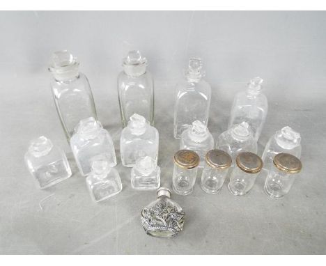 A collection of vintage glass bottles and stoppers, four small jars with white metal covers and similar.