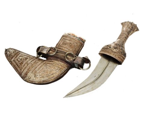 AN OMANI SILVER COLOURED METAL KHANJAR OR CEREMONIAL DAGGER with finely embossed decoration, 35cm long in red velvet case (Pr
