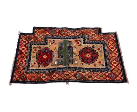 A TIBETAN SADDLE RUG
1st half 20th century, hand-knotted wool in red and beige tones, two circular red ground panels surround