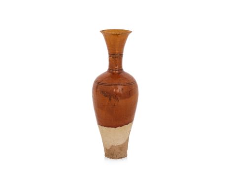 A TALL AMBER-GLAZED VASE
Liao dynasty, slender earthenware vase with ovoid body and flanged neck, incised bands around the sh