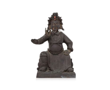 A BRONZE MODEL OF GUANDI Qing dynasty, hollow cast bronze modelled seated on throne, wearing robe over armour, stroking his c
