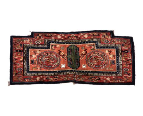 A DRAGON MEDALLION TIBETAN SADDLE RUG
1st half 20th century, hand-knotted wool in red tones with blue borders, two central dr