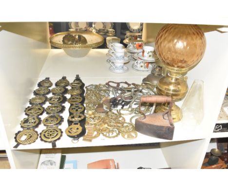 A large group of horse brass, sold together with a brick float iron, two vintage oil lamps and glass chimney's ect
