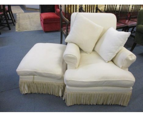 A late 20th century cream armchair with matching pouffe having a fringe detailLocation: C 