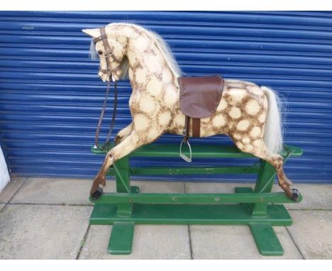 A dappled brown and cream painted rocking horse on a green painted stand. 