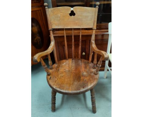 A late 19th / early 20th century fireside armchair with solid round seat, stick back and turned legs 