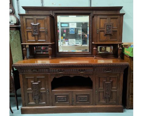 A late Victorian carved oak sideboard in the Arts & Crafts style, the raised mirror back with twin side cupboards over 3 frie