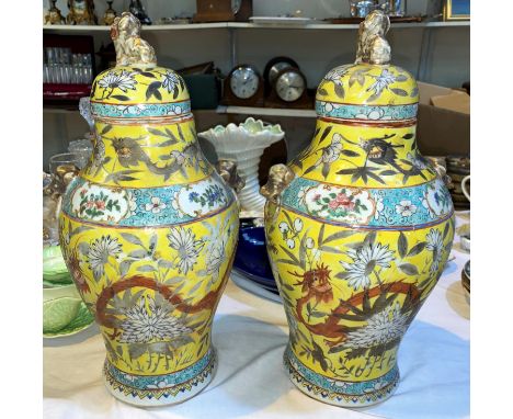 A Chinese pair of baluster covered vases with temple dog finials, mask and ring side handles, decorated in the famille jaune 