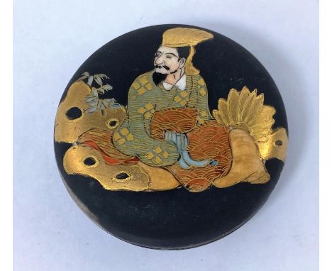 A Japanese satsuma miniature circular ceramic lidded pot decorated with traditional dressed man with black matt finish, signa