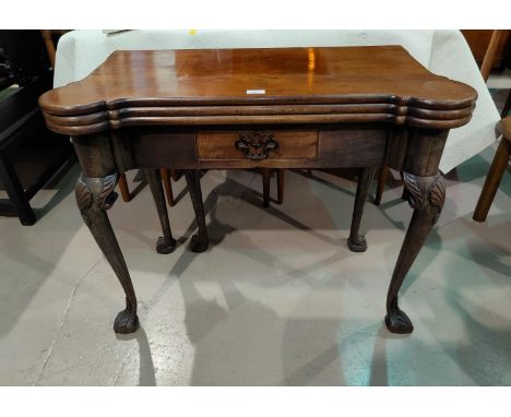 An early/mid Georgian mahogany card table with triple folding top and outset rounded corners, frieze drawer, on shell carved 