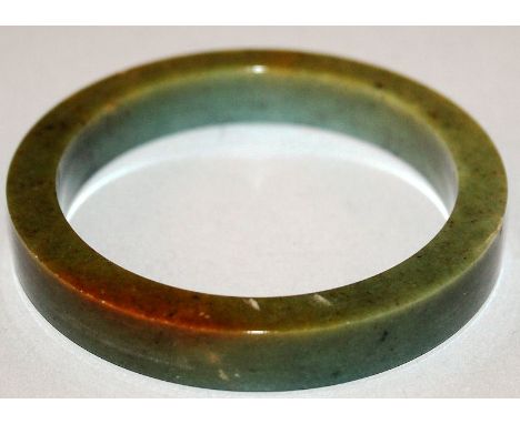 A HEAVY GREEN JADE BANGLE.
