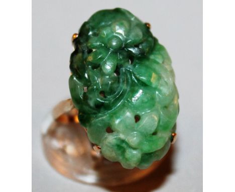 A SUPERB CHINESE CARVED GREEN JADE OVAL RING pierced and carved with flowers, set in yellow gold.