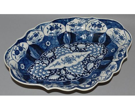AN 18TH CENTURY WORCESTER SCALLOPED OVAL SHAPED DISH decorated after Chinese with lotus in panels and a bold floral centre (5