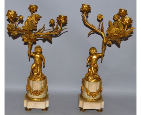 A GOOD PAIR OF 19TH CENTURY FRENCH ORMOLU AND WHITE MARBLE THREE LIGHT CANDELABRA formed as a pair of cupids holding three fl