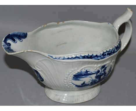 A WORCESTER SAUCEBOAT decorated with Oriental style landscape vignettes in moulded cartouches in under-glaze blue workman’s m