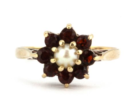 A 9ct gold ring set with a small pearl surrounded by garnets. (O), W. 2.1g.