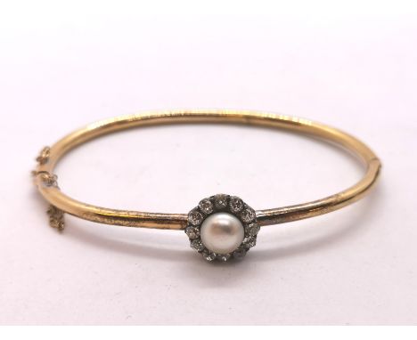 An antique 15ct gold bangle set with a natural pearl surrounded by diamonds. Bangle width 6.5cms. With original box.