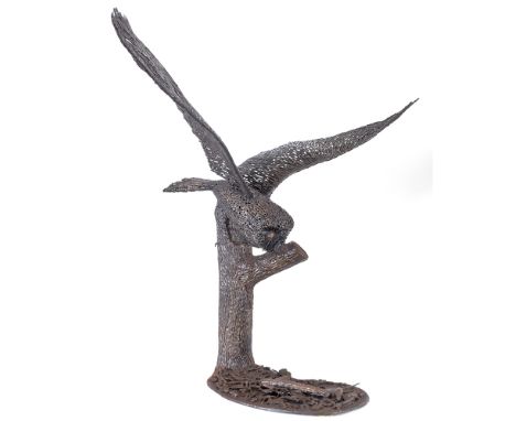 SCULPTURE OF AN OWL IN FLIGHT its wings outstretched, supported by a tree trunk on a shaped base, by Bruce Weir, blacksmith/a