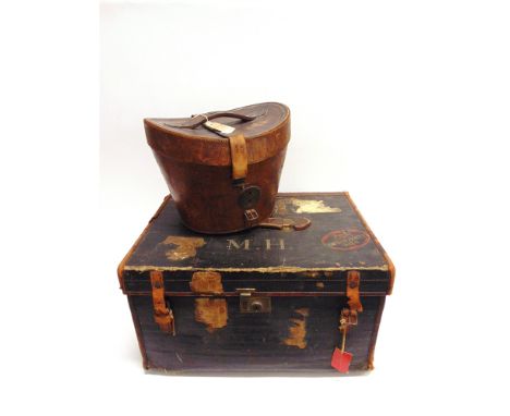 AN OVAL LEATHER HAT BOX and a rectangular canvas trunk with the initials 'M.H.' and decorated with assorted travel labels, ha