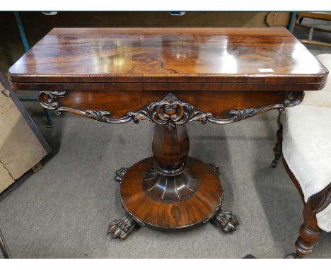 A Victorian rosewood veneered card table with folding baize lined top over a bulbous column and a platform base with paw feet
