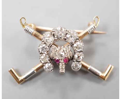 An Edwardian yellow metal, ruby and diamond set hunting brooch, modelled as a horseshoe and fox head upon crossed riding crop
