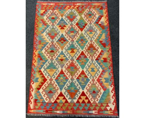 An Anatolian Kilim rug / carpet, woven with an arrangement of diamonds within a field of red, turquoise, and pale blue, 185cm