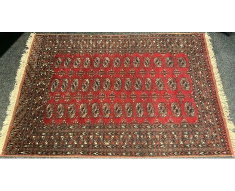 A Turkman style hand-knotted Persian rug / carpet,  the central field with all-over medallion design on a red ground, 186cm x