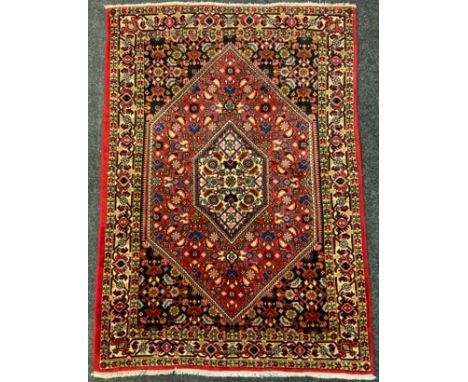 A Bidjar rug / carpet, intricately woven with stylised floral motifs in shades of red, indigo and blue, 146cm x 104cm. 