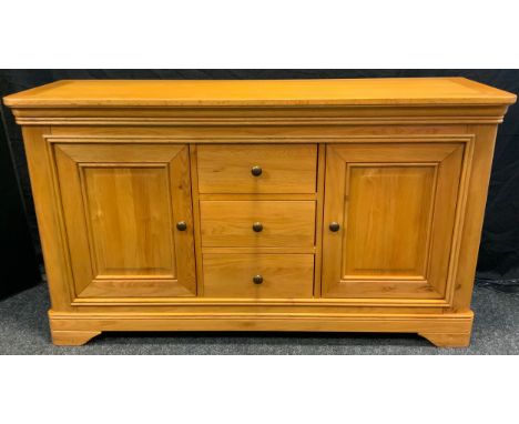 A golden tone light oak sideboard, oversailing top above three central drawers and two cupboard doors, moulded plinth, bracke