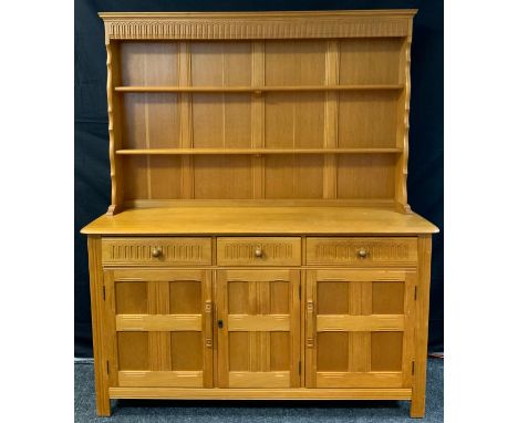 An Ercol style light oak dresser, the top with two teirs of shelving, above a base with three short drawers and three cupboar
