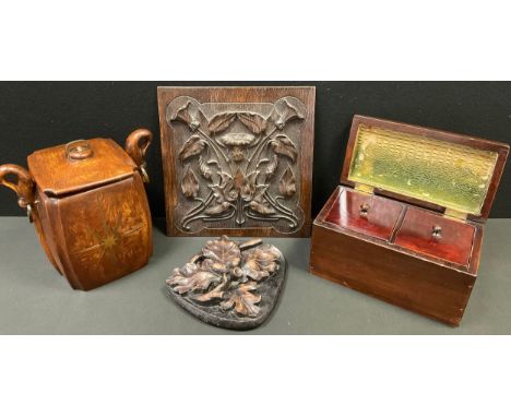 A carved brass inlaid oak tea caddy. shaped waisted body, ring and fish loop handles, 21.5cm high, 23.5cm wide;  a carved oak