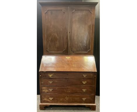 A George III  mahogany bureau bookcase, the moulded cornice above two panelled doors, the base with fall front, bracket feet,