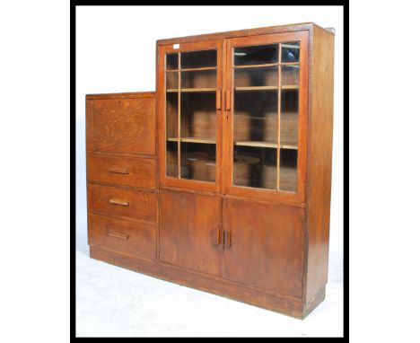 A 1930's Art Deco oak cabinet bureau bookcase of unusual configuration, glazed doors over panel doors opening to reveal adjus