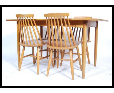 A 1970's retro teak wood extending dining table being raised on turned legs with fitted frieze having extending table top abo