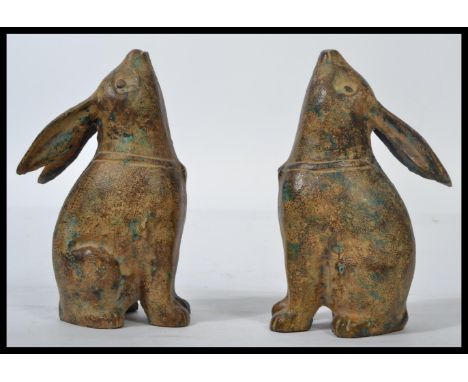 A pair of cast bronze figurines modelled as rabbits looking skywards whilst sat on their hind legs. it is 22cm in height