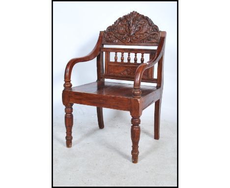 A carved hardwood chair - armchair being raised on turned legs united by peripheral stretchers, panel seat with carved armori