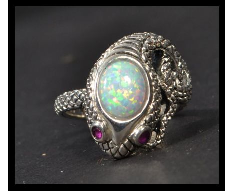 A sterling silver ring in the form of a snake with opal panel heat and inset ruby eyes. Weighs 7 grams.
