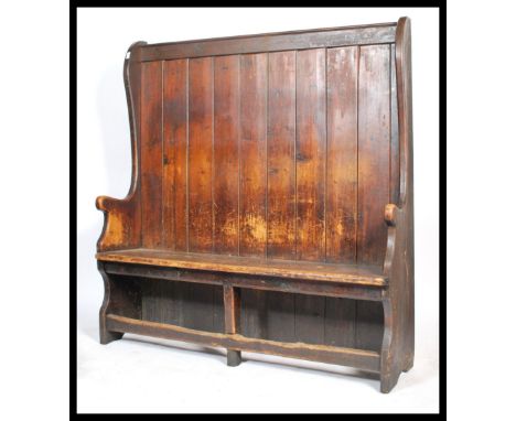 A large Victorian pine hall settle having a planked seat raised over pierced apron the underside. The seat flanked by carved 