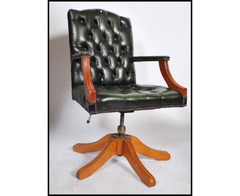 A 20th century green leather Chesterfield style deep button back swivel mahogany framed captains office desk chair raised on 
