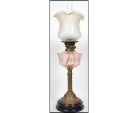 An early 20th Century oil lamp having a flute and tulip style shade raised above a faceted reservoir on top of a cast metal t