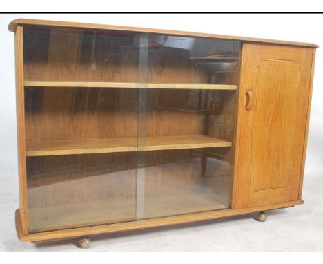 A mid century oak display cabinet bookcase room divider in the manner of Ercol, believed to be Priory. Raised on shaped base 