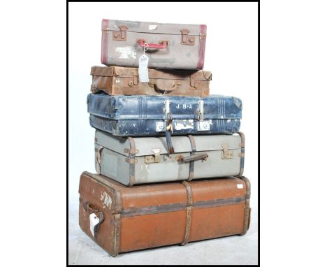 A stack of 5 vintage 20th century suitcases to include a canvas bound wooden steamer trunk, mid century blue and coloured exa