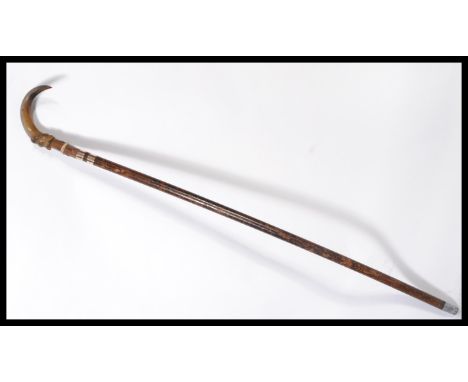 A vintage 20th century walking stick cane having a tapering wooden shaft with white metal silver collar and shaped handle in 