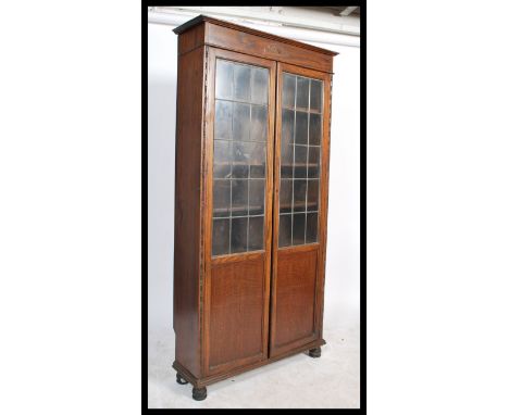 A vintage 20th century circa 1920's oak glazed tall library bookcase cabinet. The cupboard two full length leaded glazed and 