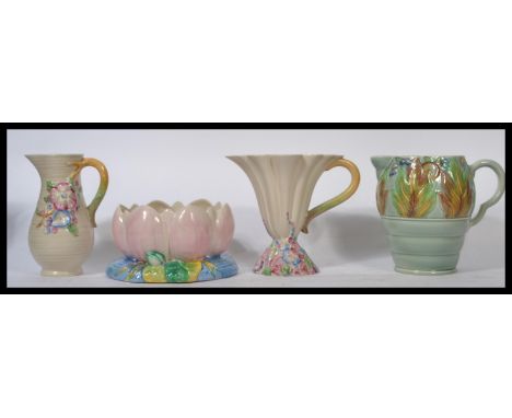 Clarice Cliff A group of four Art Deco pieces of Clarice Cliff ceramics to include three water jugs and a ' Lotus ' pattern b