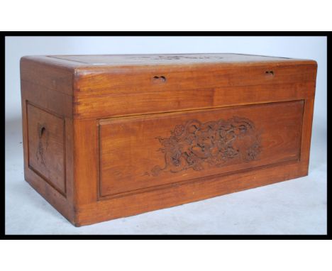 A mid 20th century Chinese camphorwood blanket box chest with carved scenes in relief having plain panel sides, hinged top ab