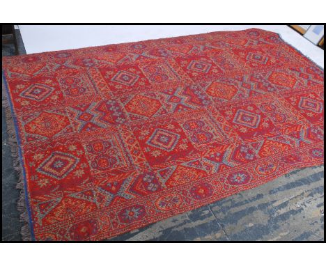 A large Oriental Shiraz style carpet - rug having red ground with multiple medallions with geometric decoration and borders e