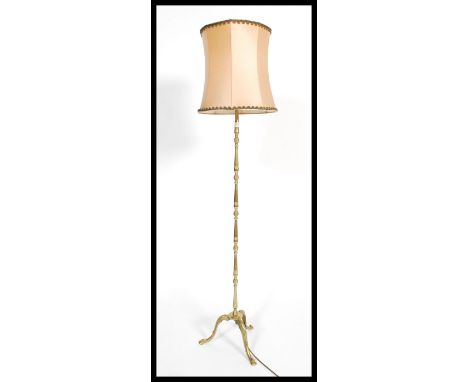 A good quality 20th century brass standard lamp being raised on spalyed legs with pad feet having a cylinder lamp shade atop